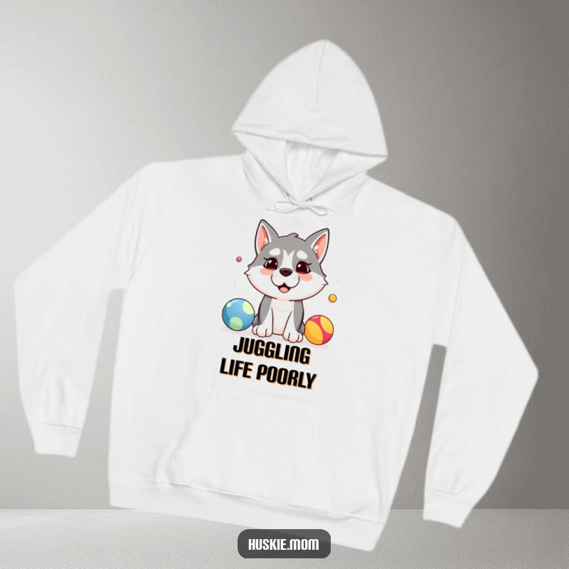 Funny hoodie showing a silly husky dog attempting to juggle three colorful balls with a comical expression, perfect for cozy humor.